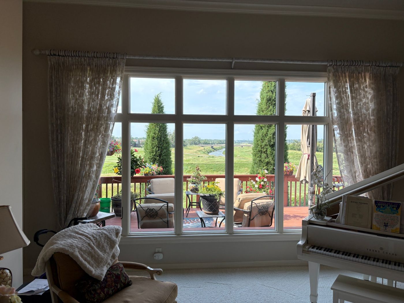Spotless picture window looking out over a deck and green park