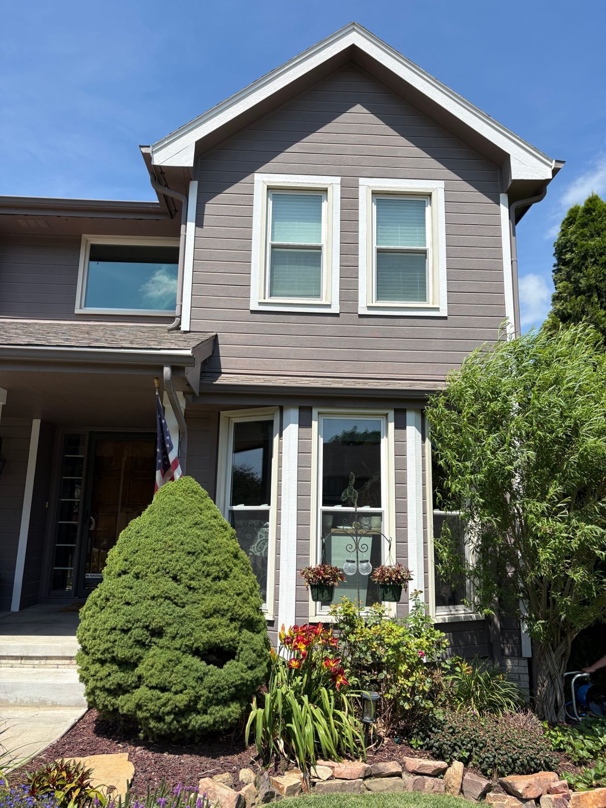 Two-story gray home with sparkling clean windows on a sunny day